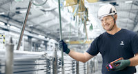 a man wearing a hard hat and gloves working in a factory