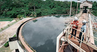 Two people talking on a metal bridge over a water tank