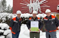 a group of men wearing hard hats and holding a certificate in front of a red building