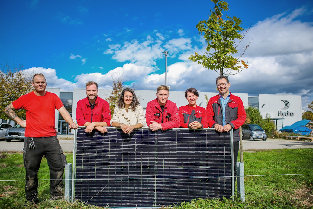 a group of people standing behind a black rectangular object with a black object in front of them