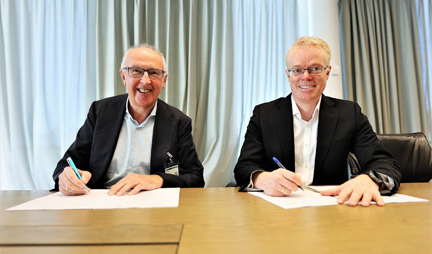 a couple of men sitting at a table with papers and pens