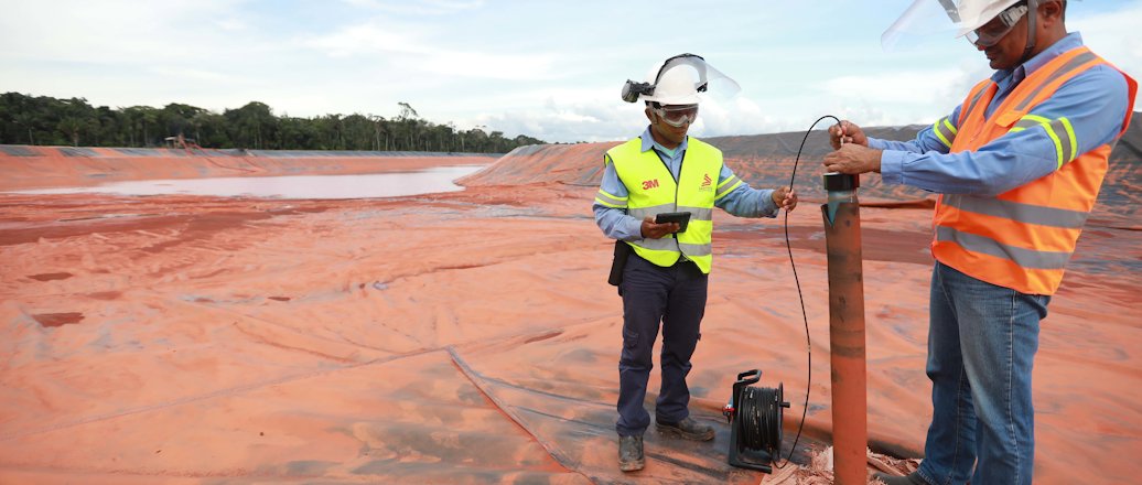two men wearing hardhats operating an instrument