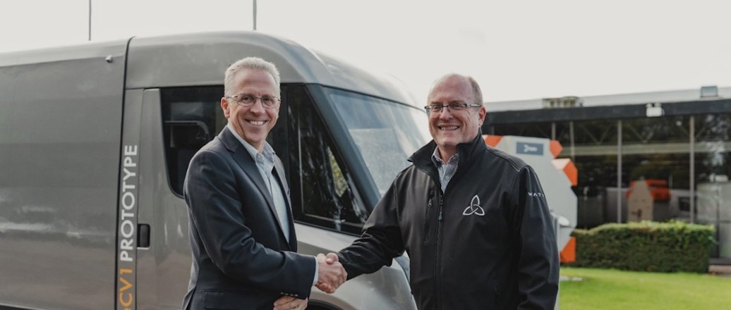 two men in suits standing in front of a van