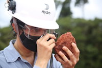 a person wearing a helmet and holding a piece of bauxite