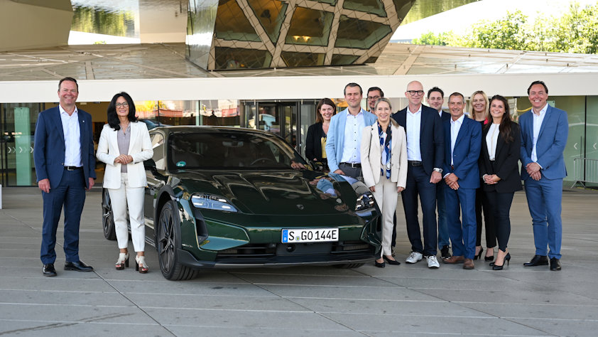 a group of people posing for a photo next to a car