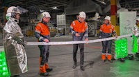 a group of people in safety gear holding a ribbon
