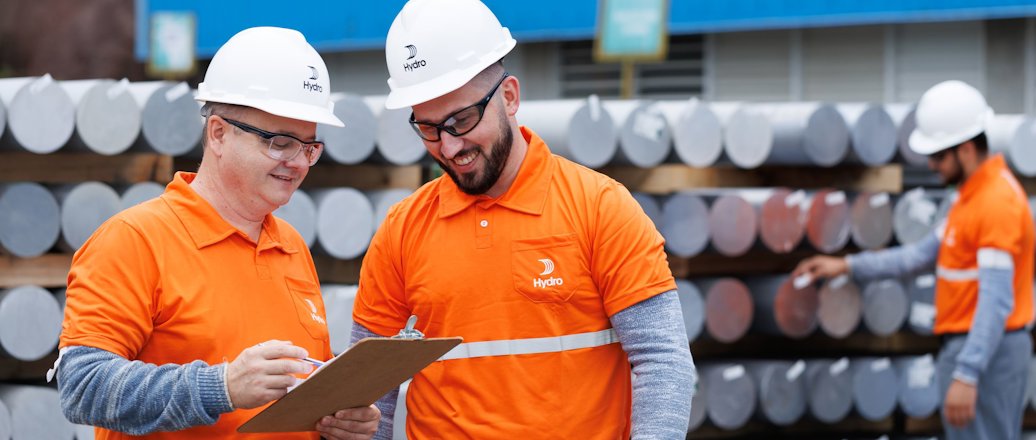 a group of men wearing hardhats and looking at a piece of paper