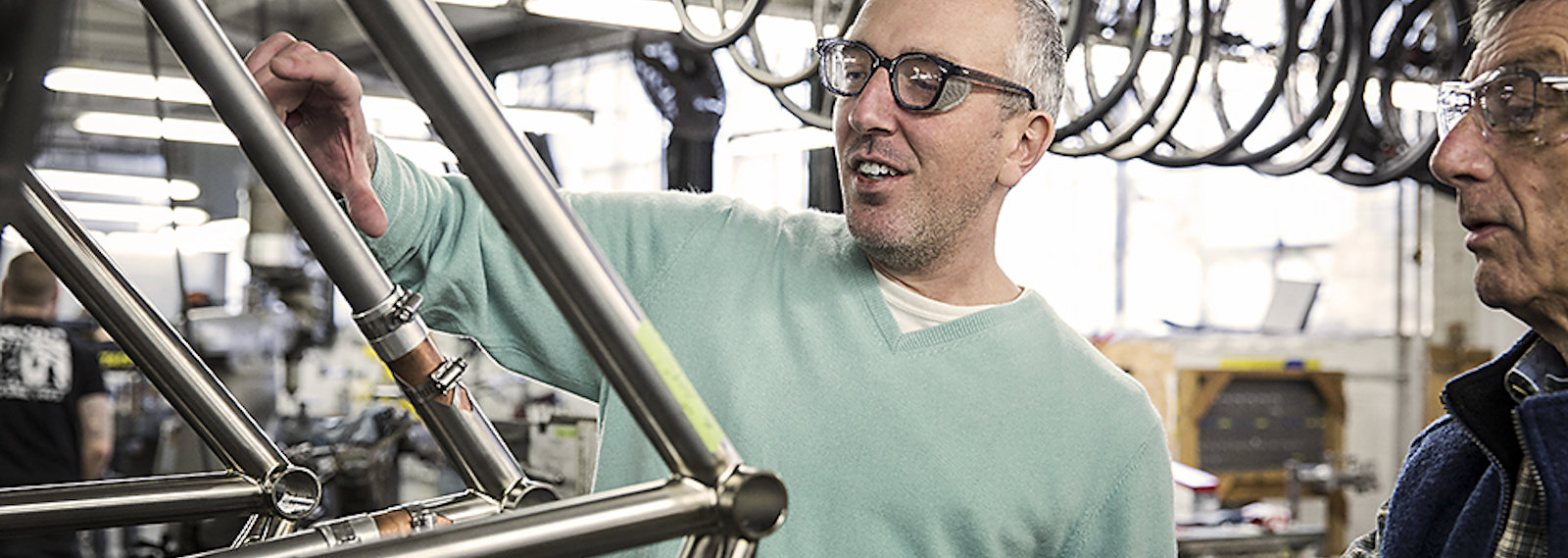 men in a bike shop, studying an aluminium frame